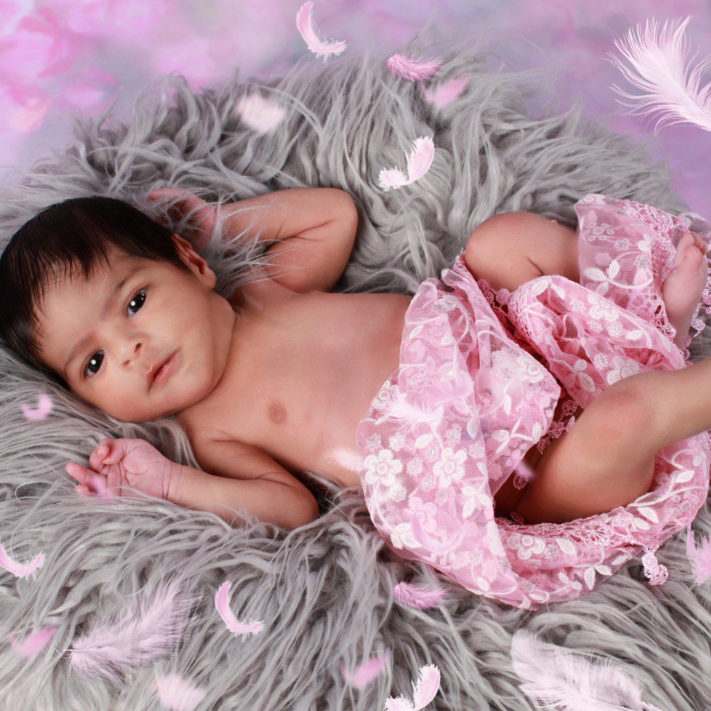 Младенец лежит на сером меховом покрывале 