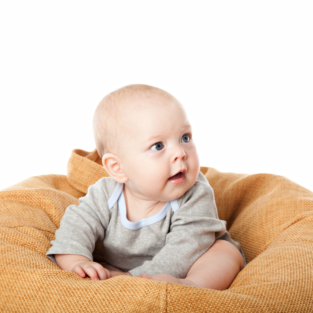 Младенец сидит на подушке на белом фоне