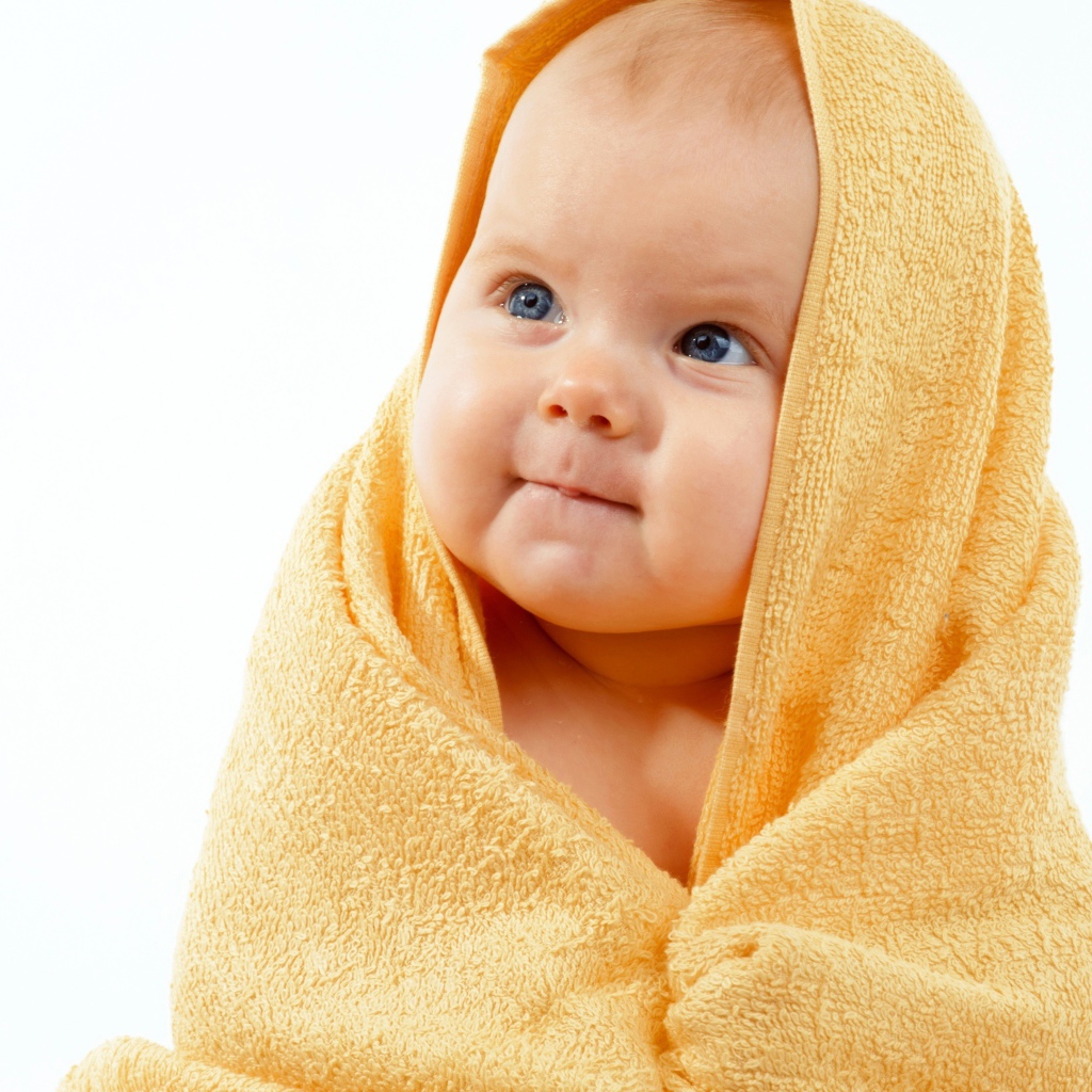 Грудной ребенок в желтом полотенце на белом фоне