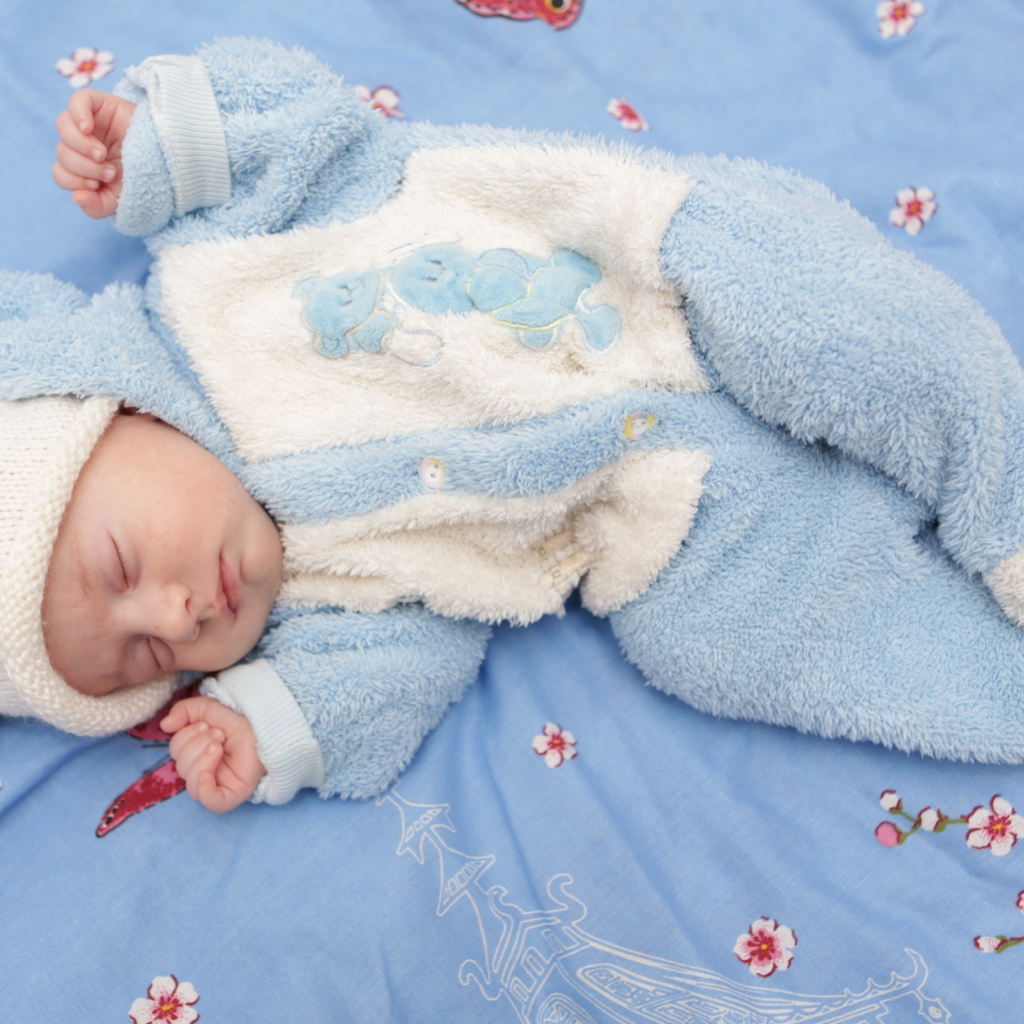 Грудной спящий ребенок в голубом костюме