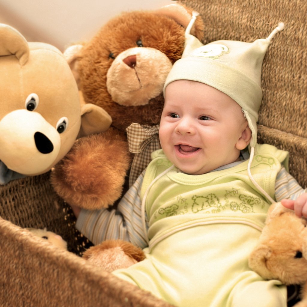 Грудной улыбающийся ребенок в корзине с игрушками