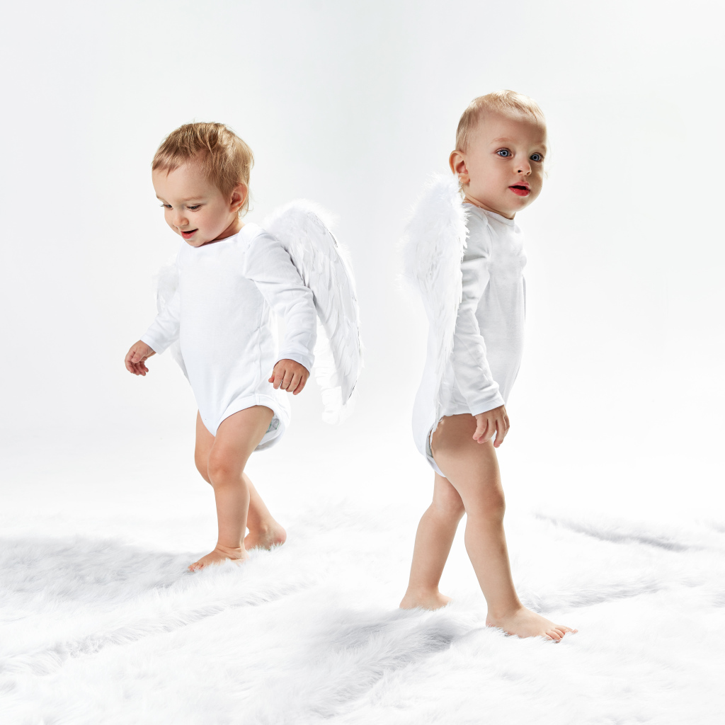 Два маленьких мальчика в костюмах ангела на белом фоне