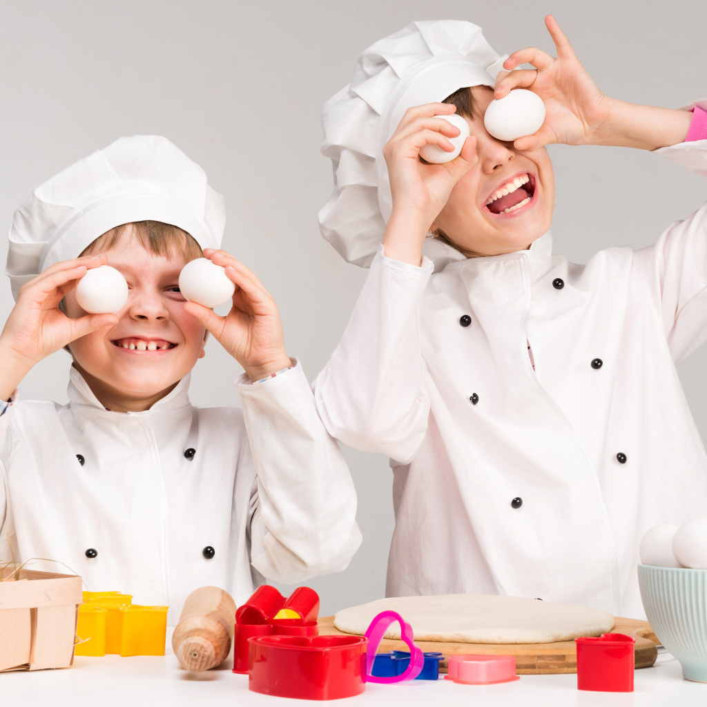 Два маленьких мальчиках в костюмах повара на кухне
