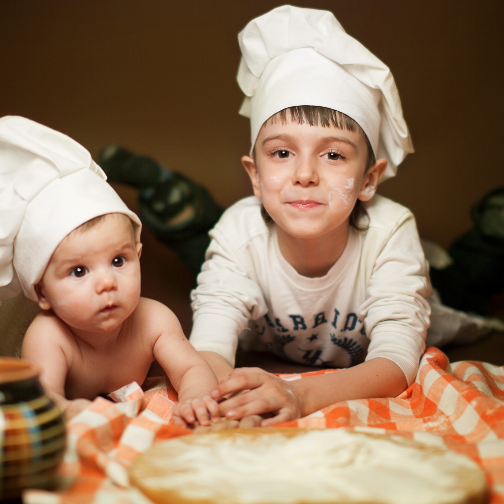 Два маленьких мальчика в шапках повара на кухне