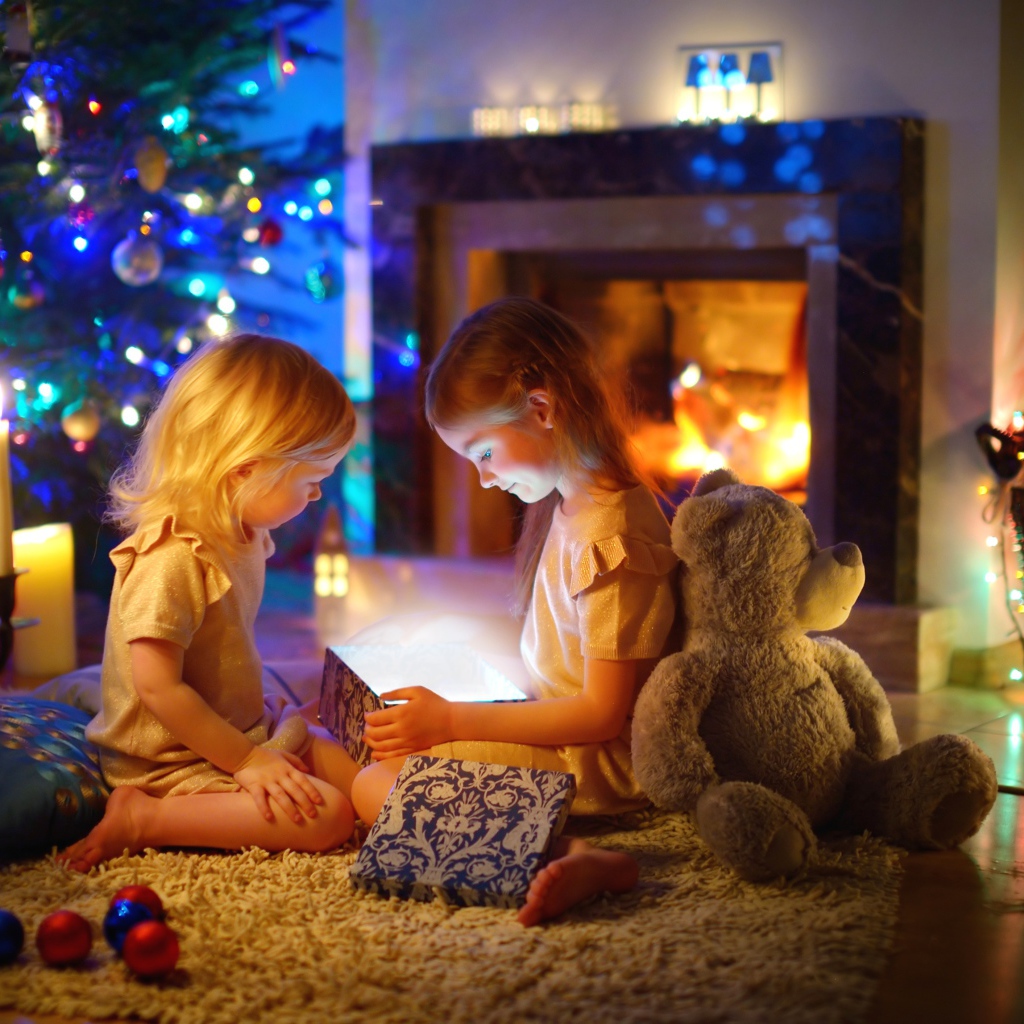 Две маленькие девочки с игрушками у камина