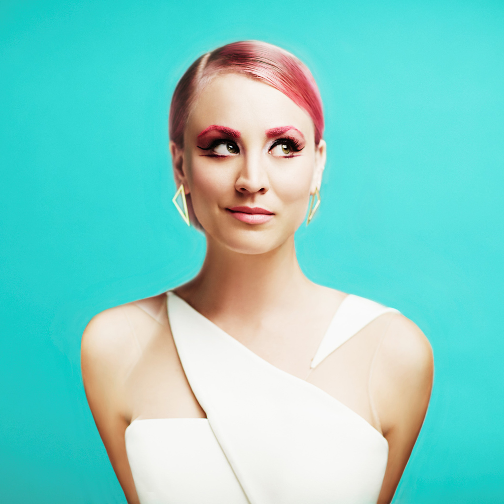 Актриса Кейли Куоко с ярким макияжем на голубом фоне