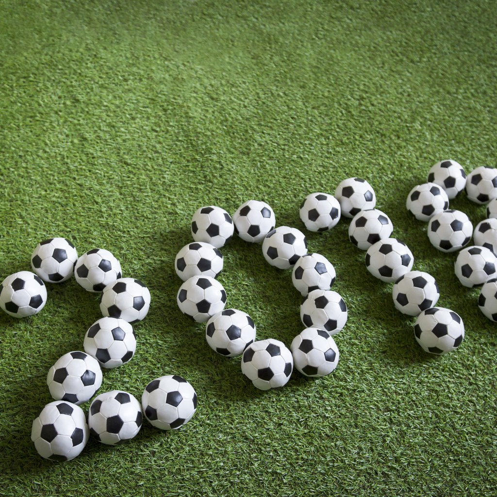 Цифры 2018 из футбольных мячей на зеленой траве