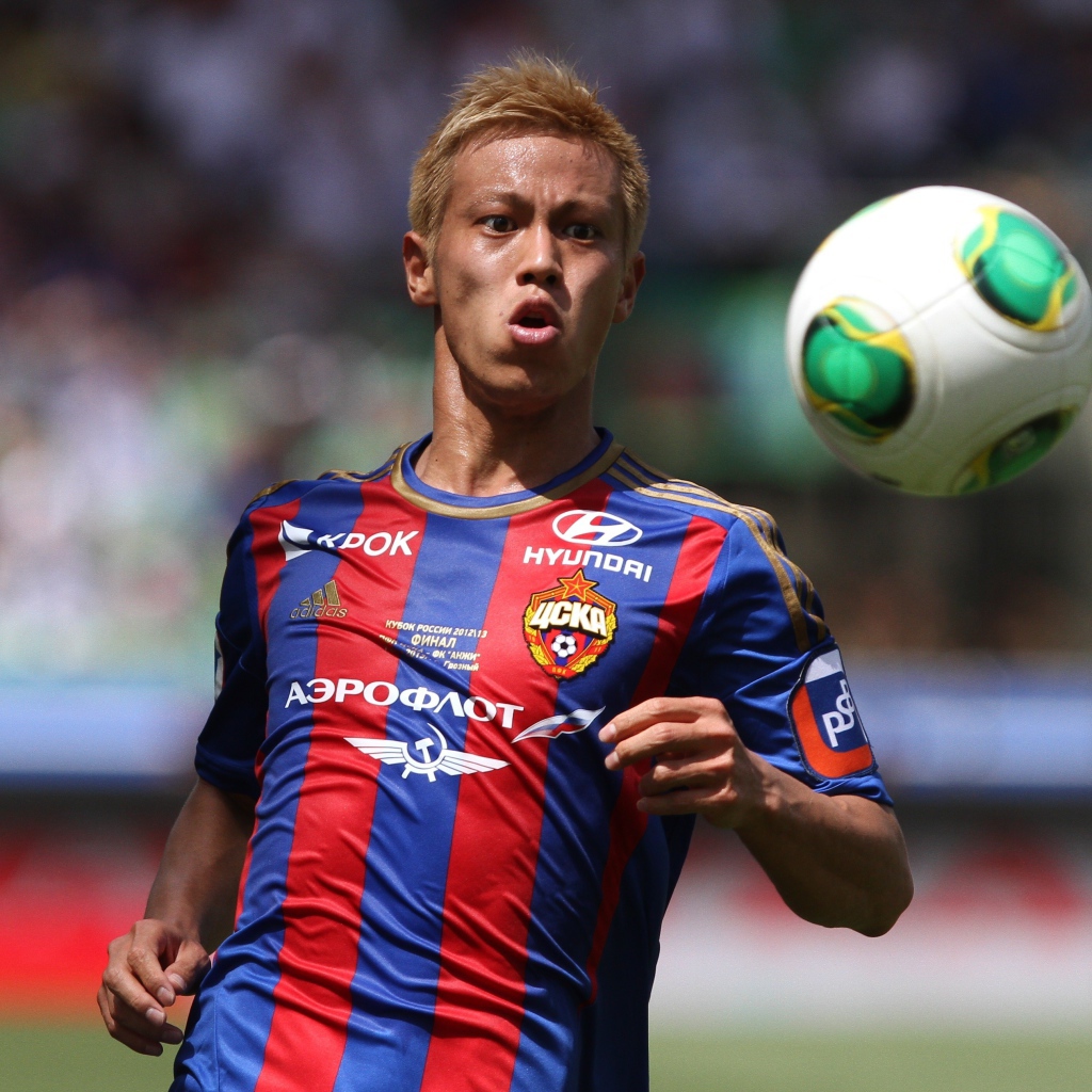 Японский футболист Кэйсукэ Хонда отбивает мяч на поле