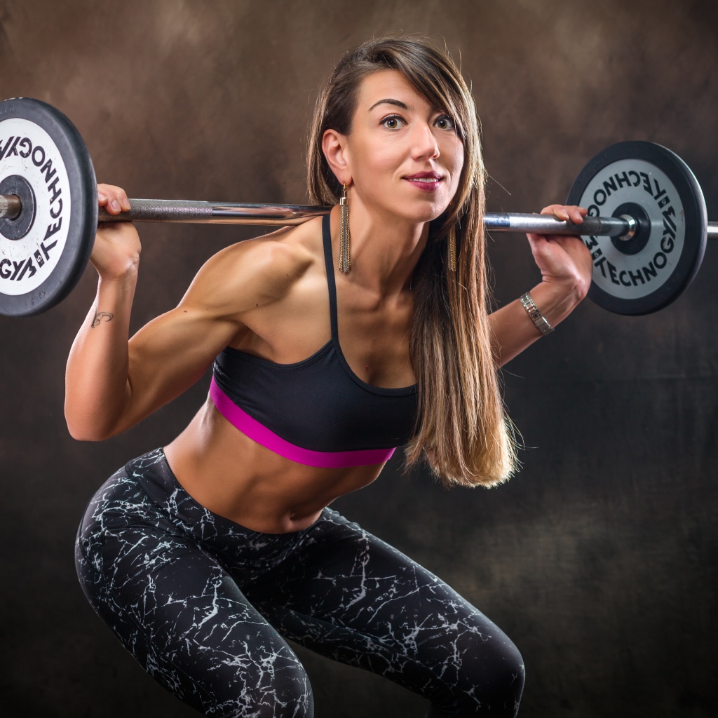 Спортивная накаченная девушка со штангой 