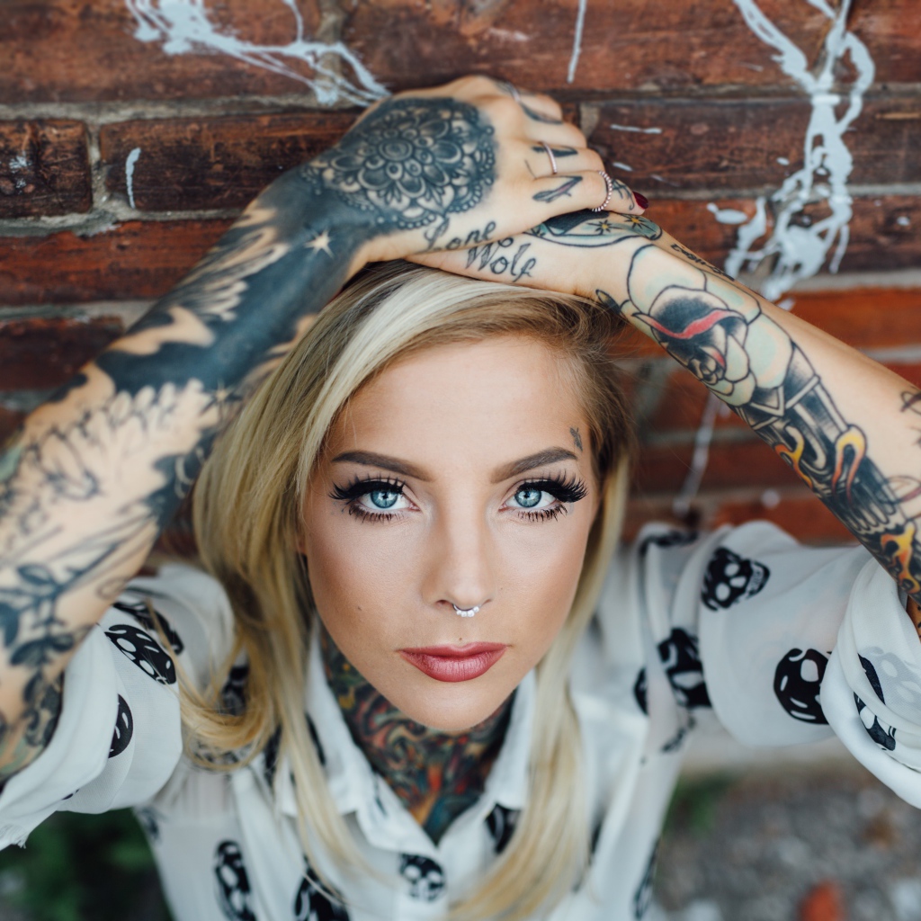Молодая девушка блондинка с татуировками по телу