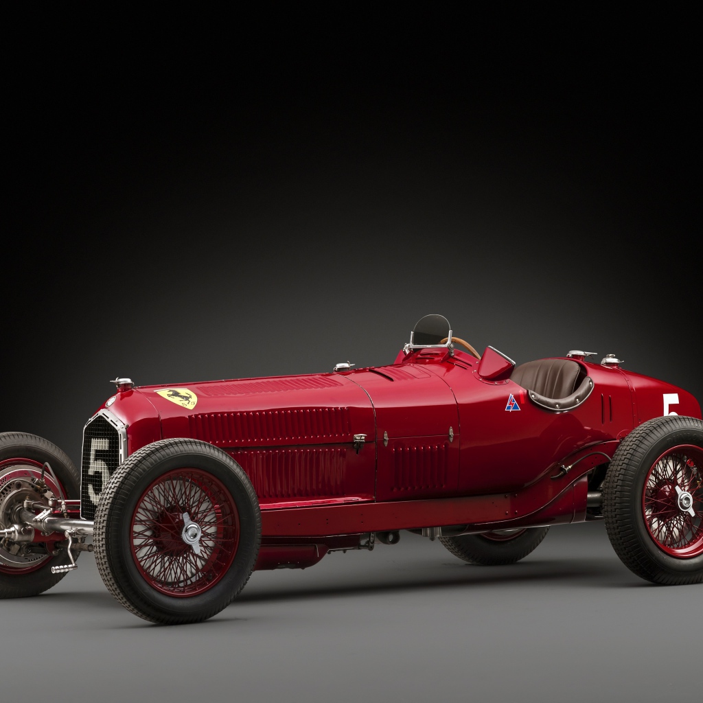 Красный ретро автомобиль Alfa Romeo на сером фоне