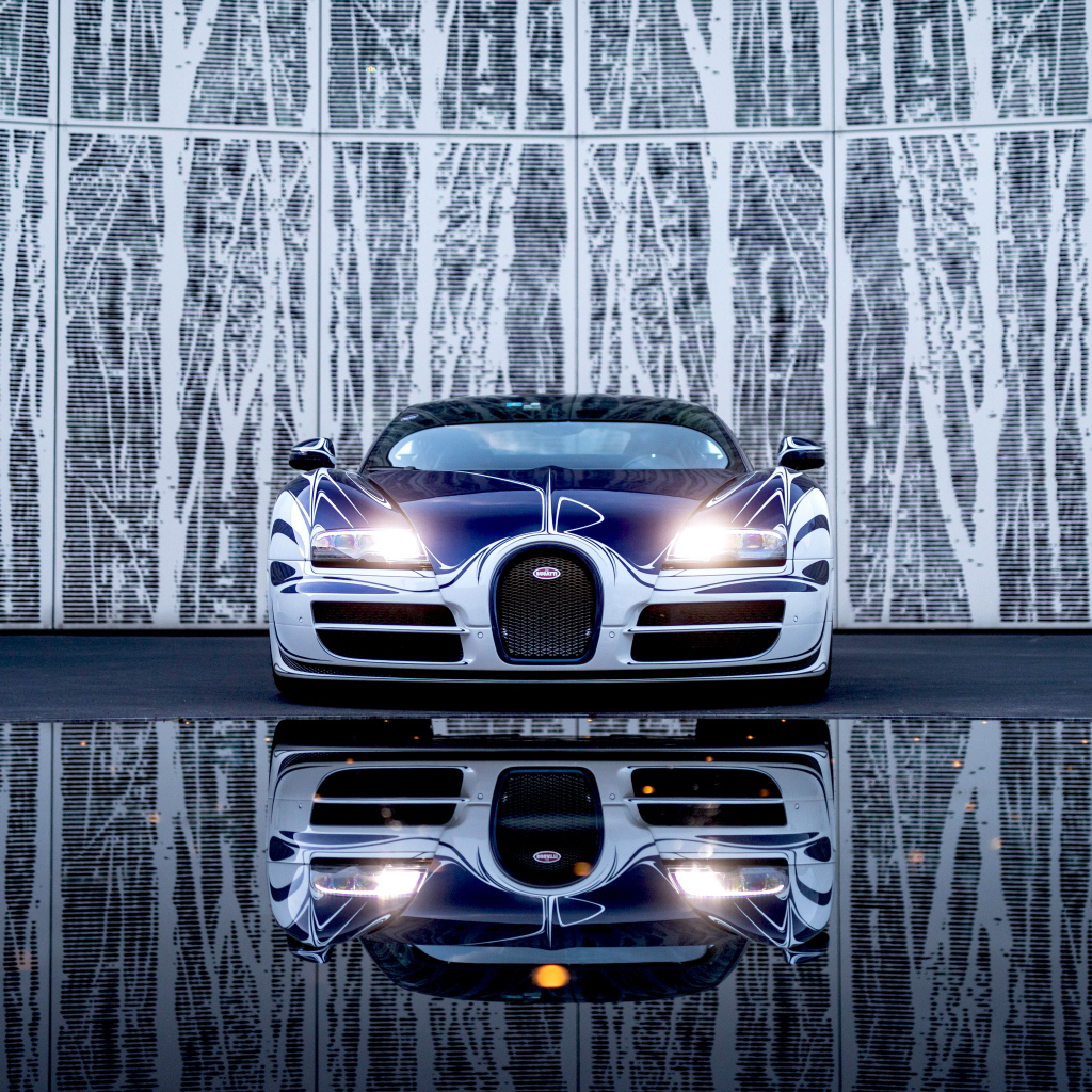 Автомобиль Bugatti Veyron Grand Sport Roadster отражается в зеркальной поверхности 