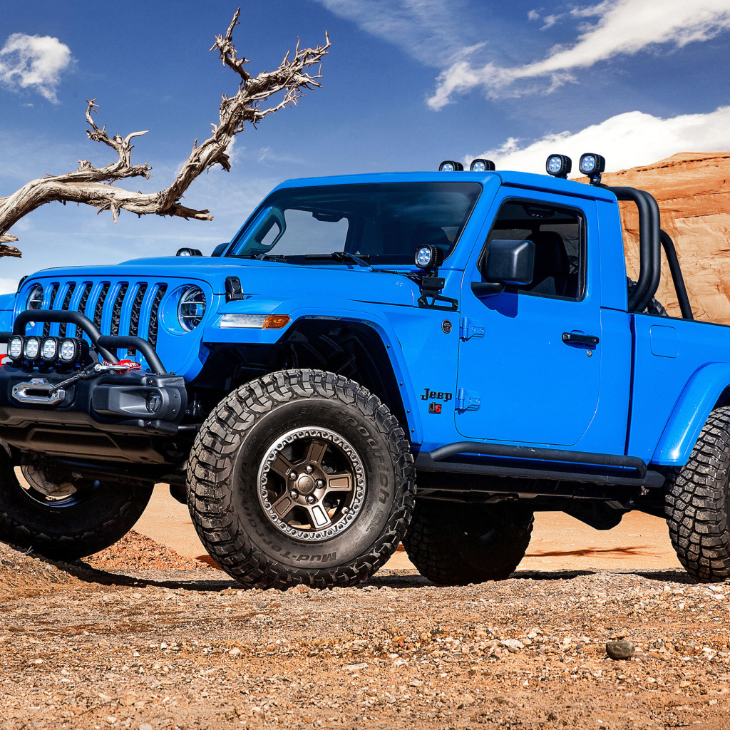 Синий пикап Jeep J6, 2019 года на фоне гор у сухого дерева