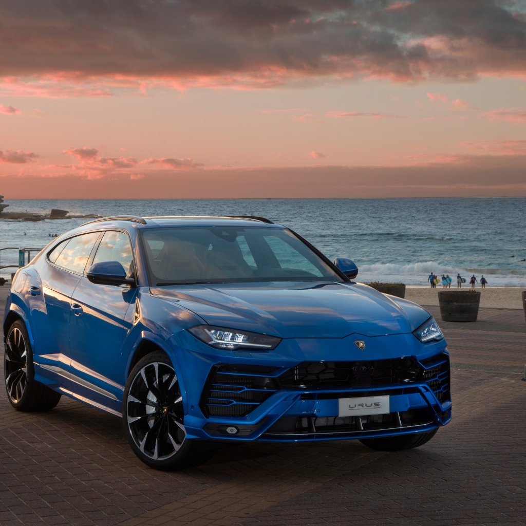 Синий автомобиль Lamborghini Urus под пасмурным небом на берегу  океана