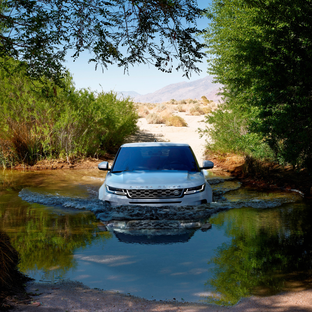 Белый внедорожник Range Rover Evoque едет по воде 