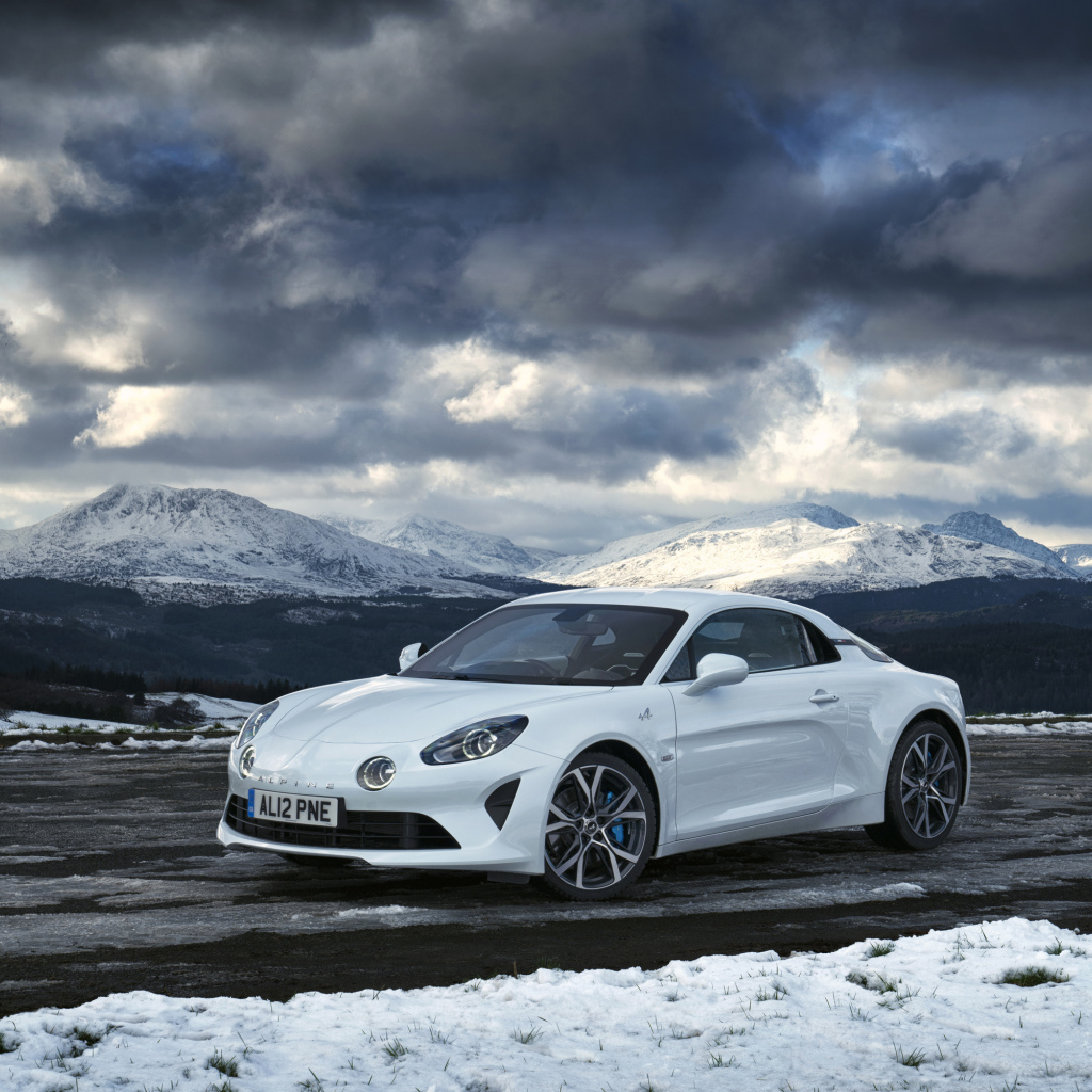 Белый автомобиль Alpine A110 на фоне гор под грозовым небом  
