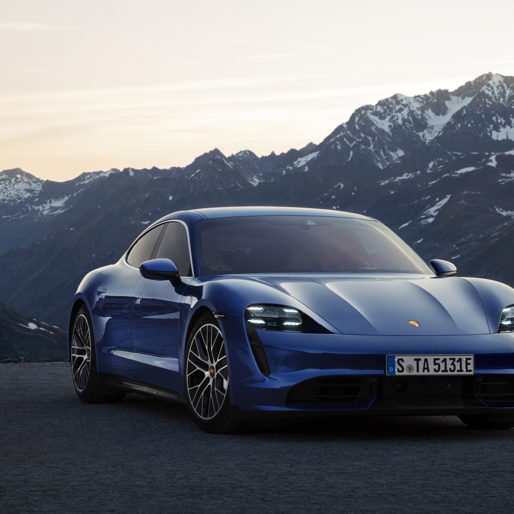 Синий стильный автомобиль Porsche Taycan Turbo 2019 года на фоне гор