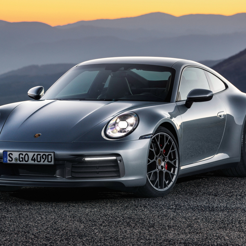 Серебристый автомобиль Porsche 911 Carrera 4S 2019 года на фоне гор 