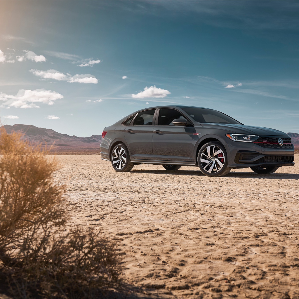 Стильный серебристый автомобиль Volkswagen Jetta на фоне неба 