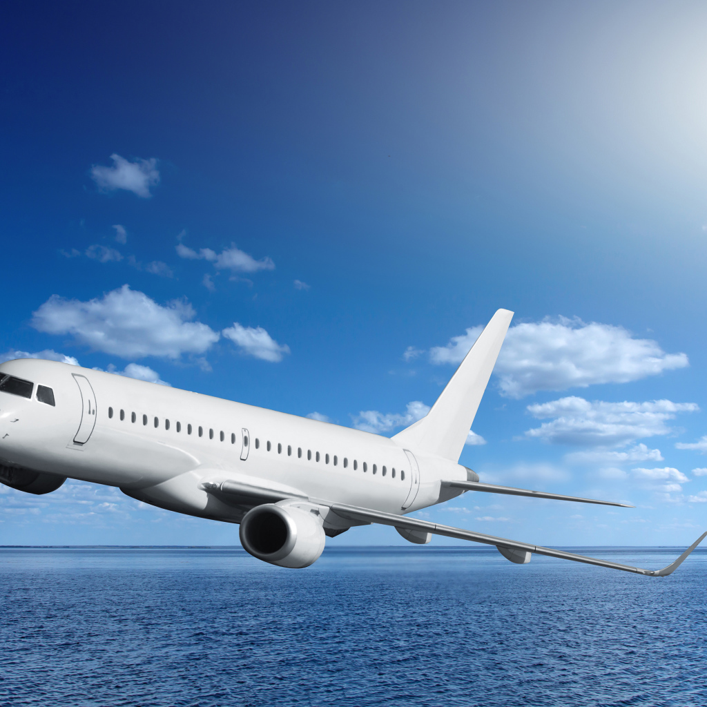 Большой белый пассажирский самолет летит над морем