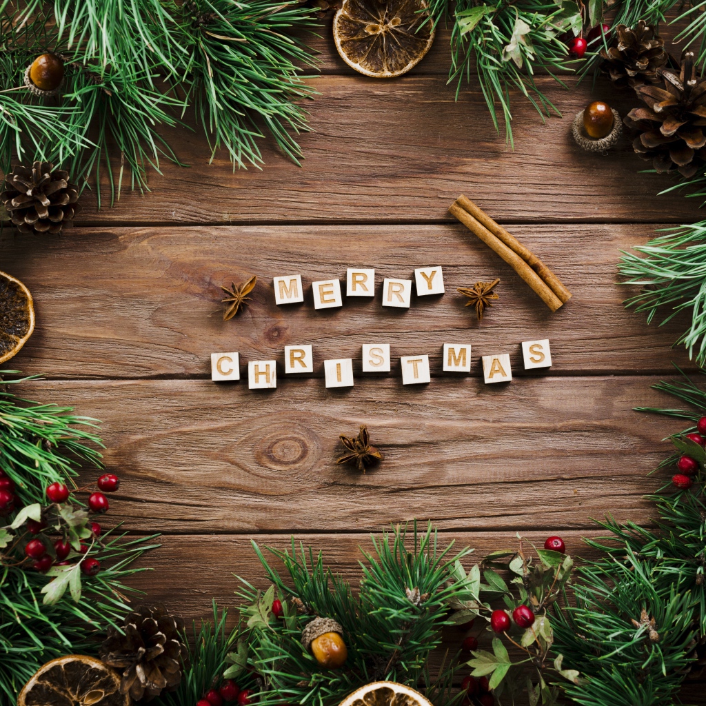 Надпись Merry Christmas на деревянном столе с еловыми ветками 