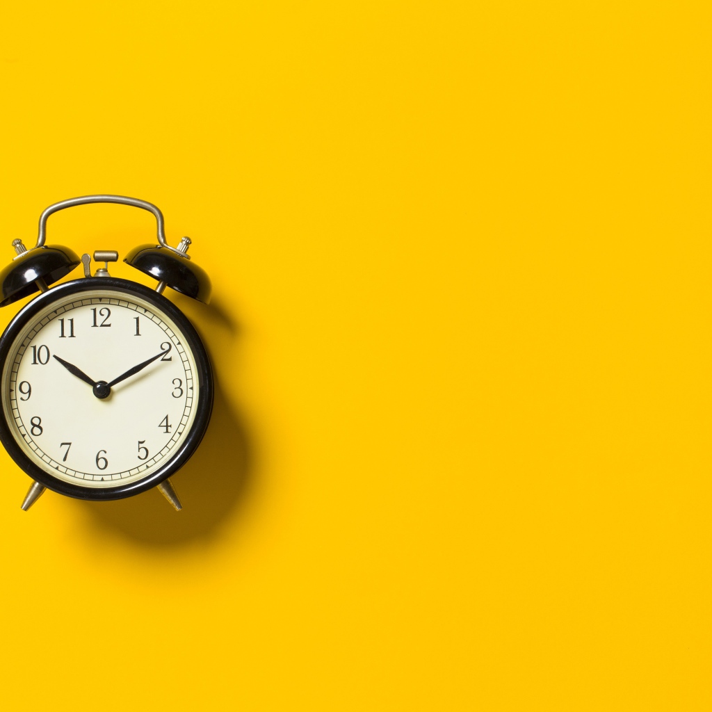 Черный будильник на желтом фоне