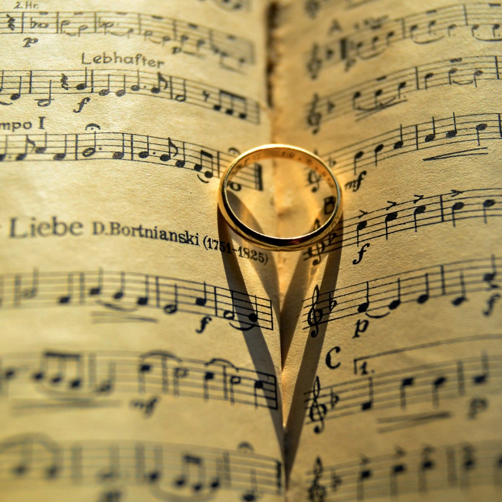 Золотое обручальное кольцо лежит на нотной тетради