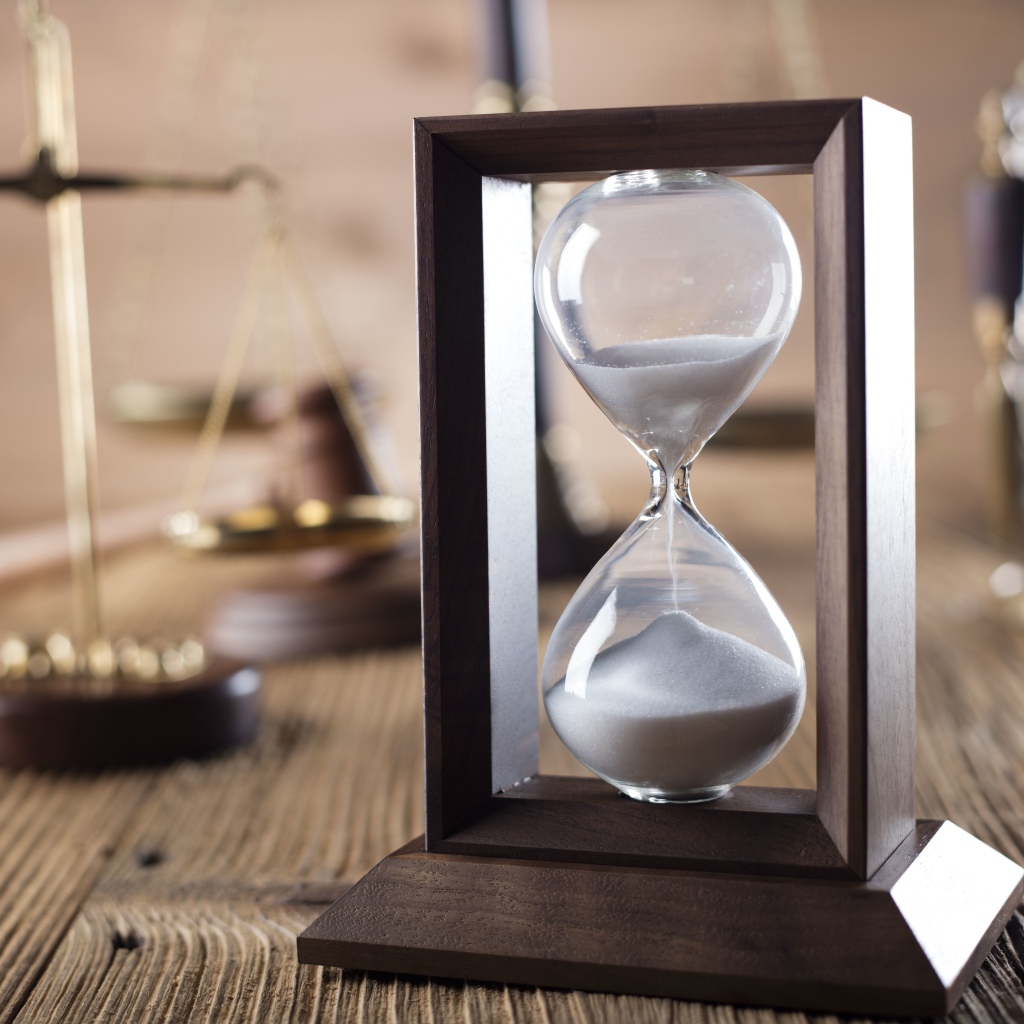 Песочные часы на столе с весами крупным планом