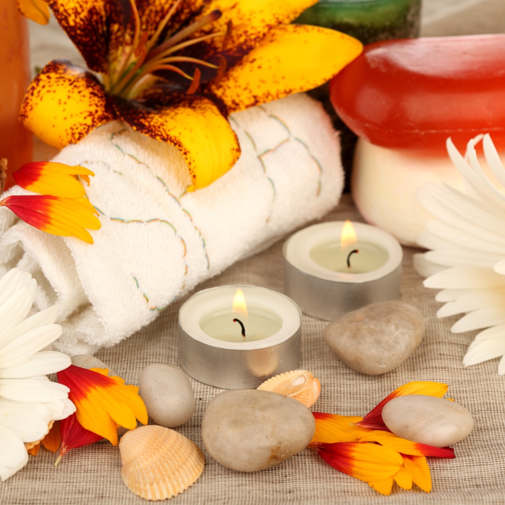 Зажженные свечи на столе с полотенцем, цветами и мылом