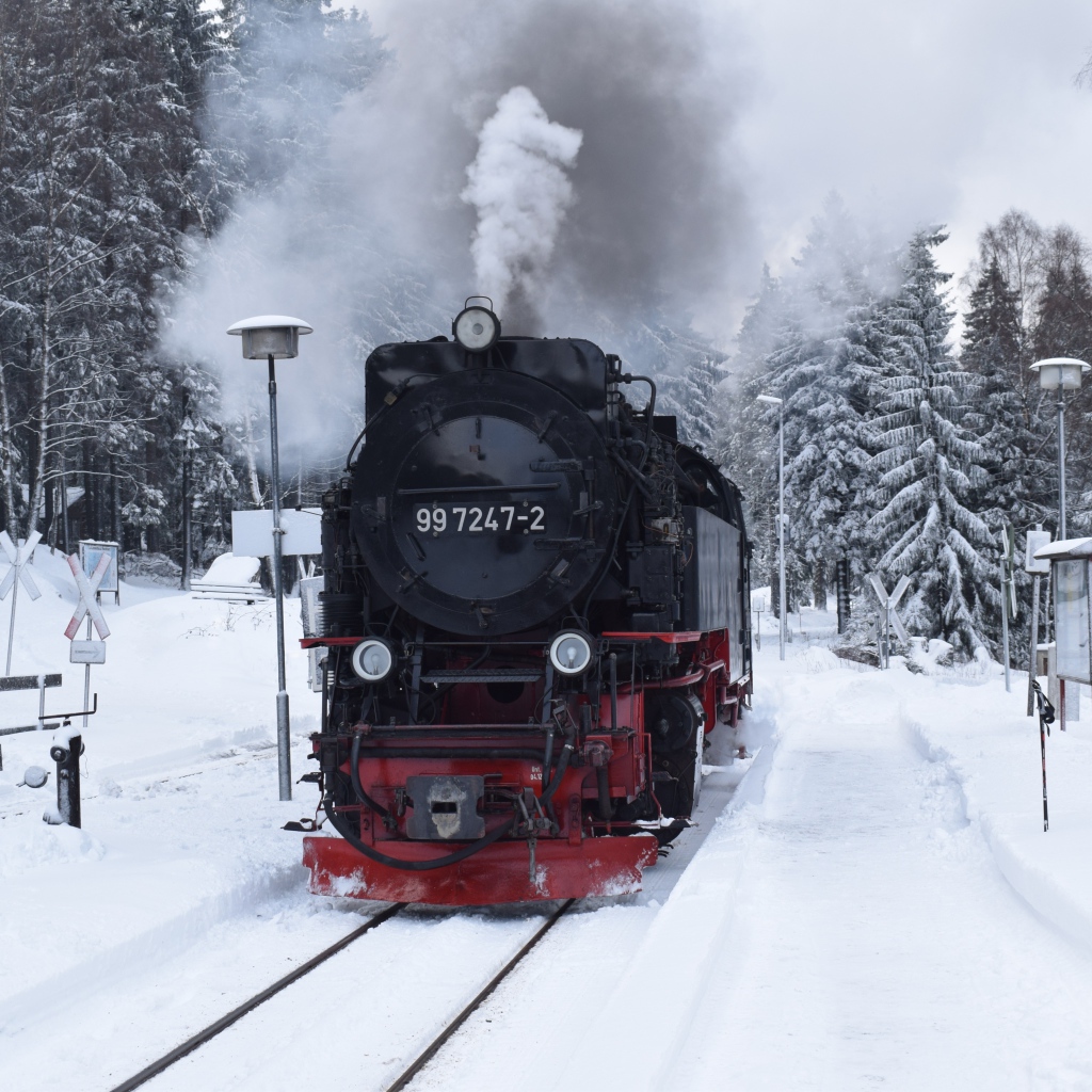 Старый локомотив на заснеженной станции у леса зимой