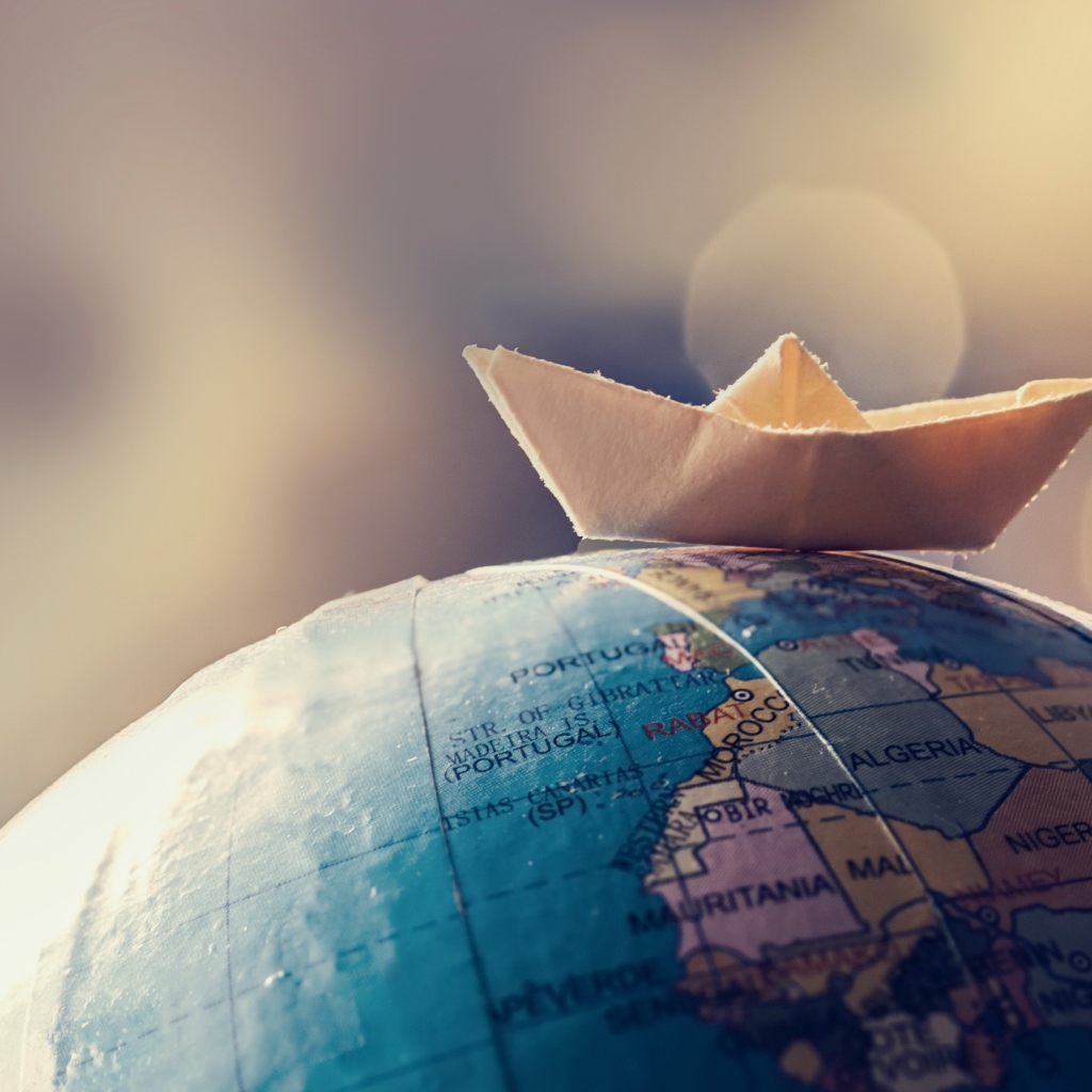 Бумажный кораблик лежит на глобусе