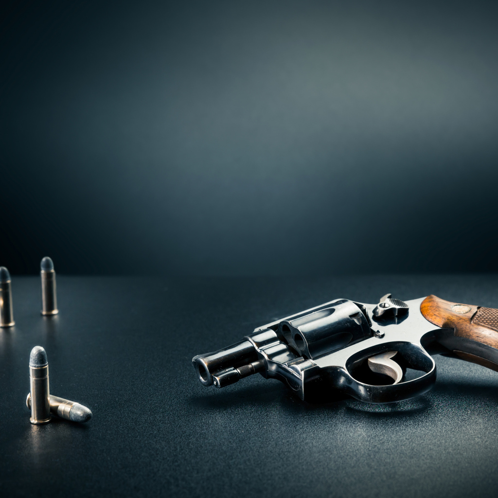 Револьвер с пулями на сером фоне