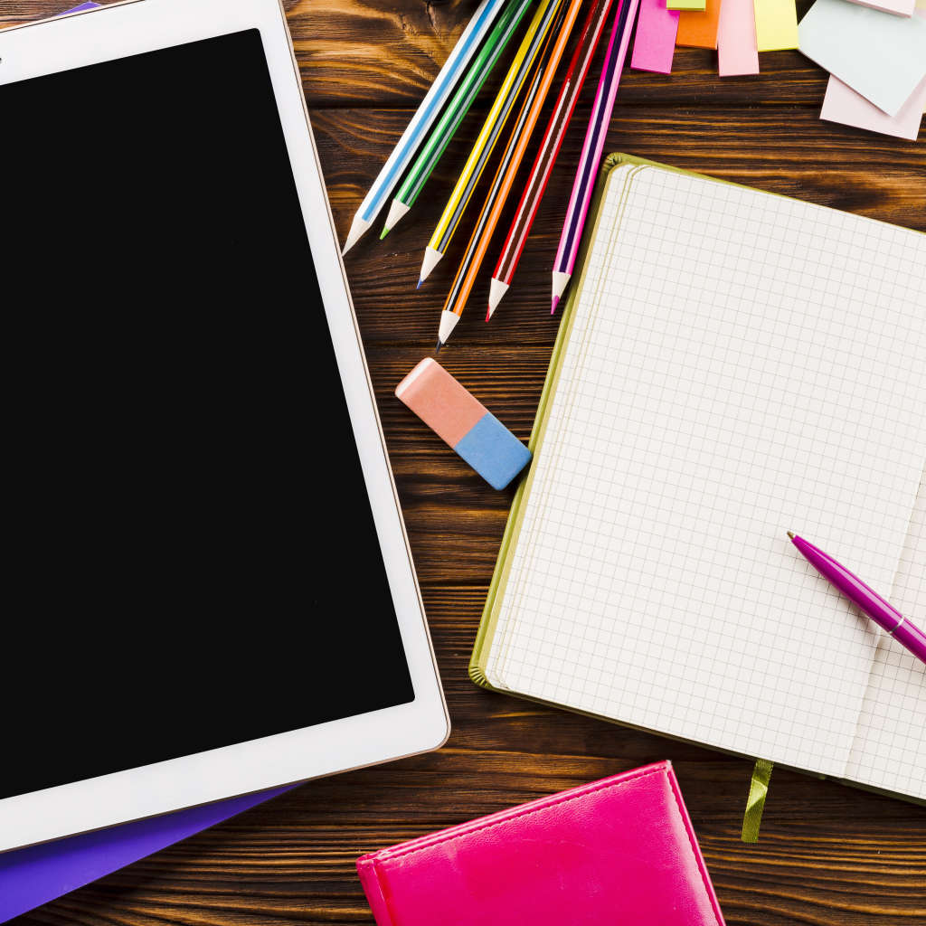 Планшет на столе с блокнотом и карандашами