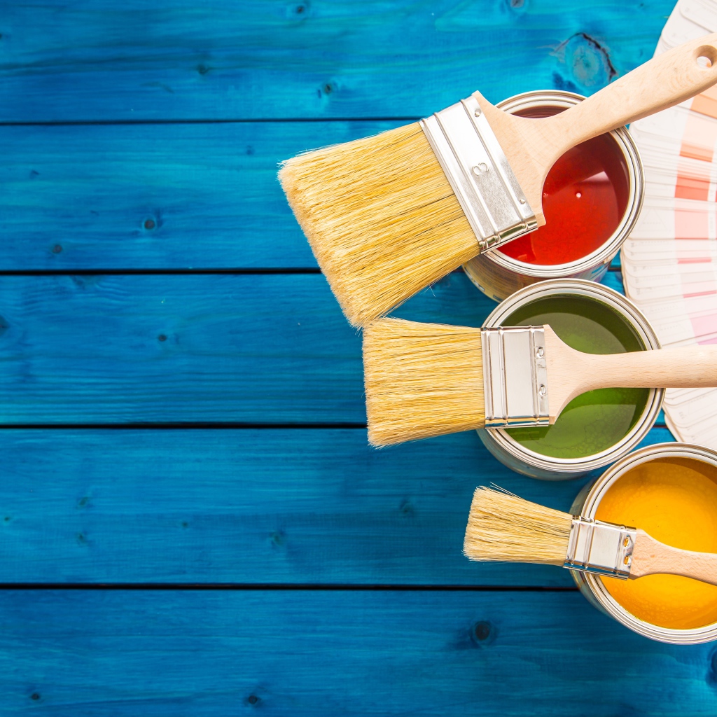 Три банки с краской и кистями на голубом фоне