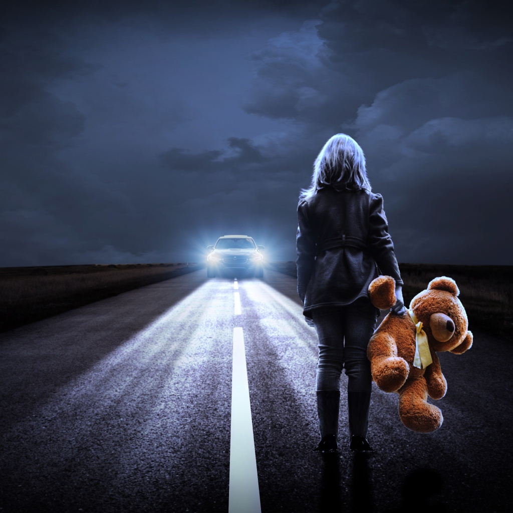 Девушка стоит на дороге с игрушечным медведем