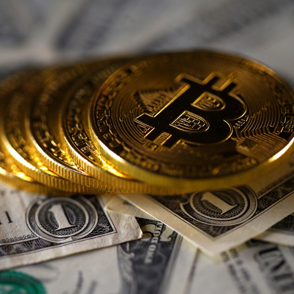 Монеты Биткоин лежат на купюрах по одному доллару