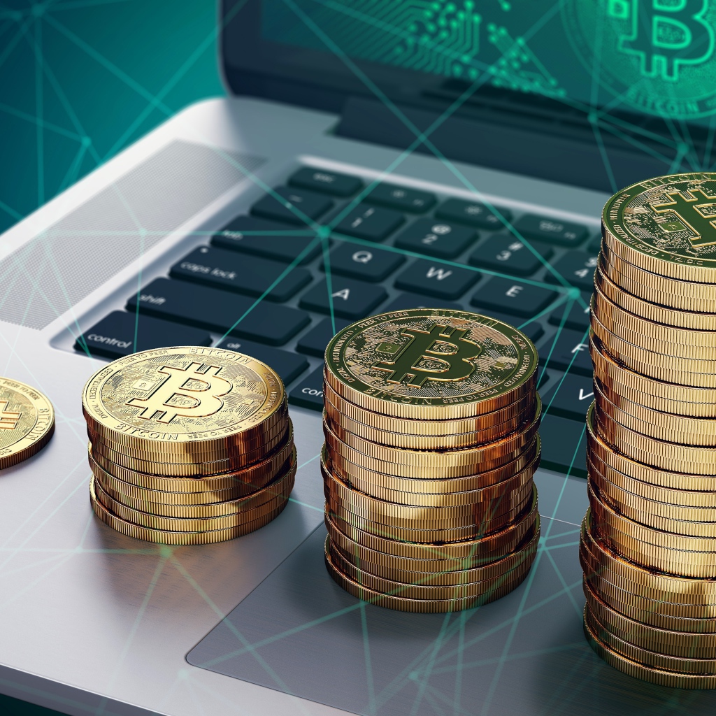 Золотые монеты Биткоин лежат на ноутбуке