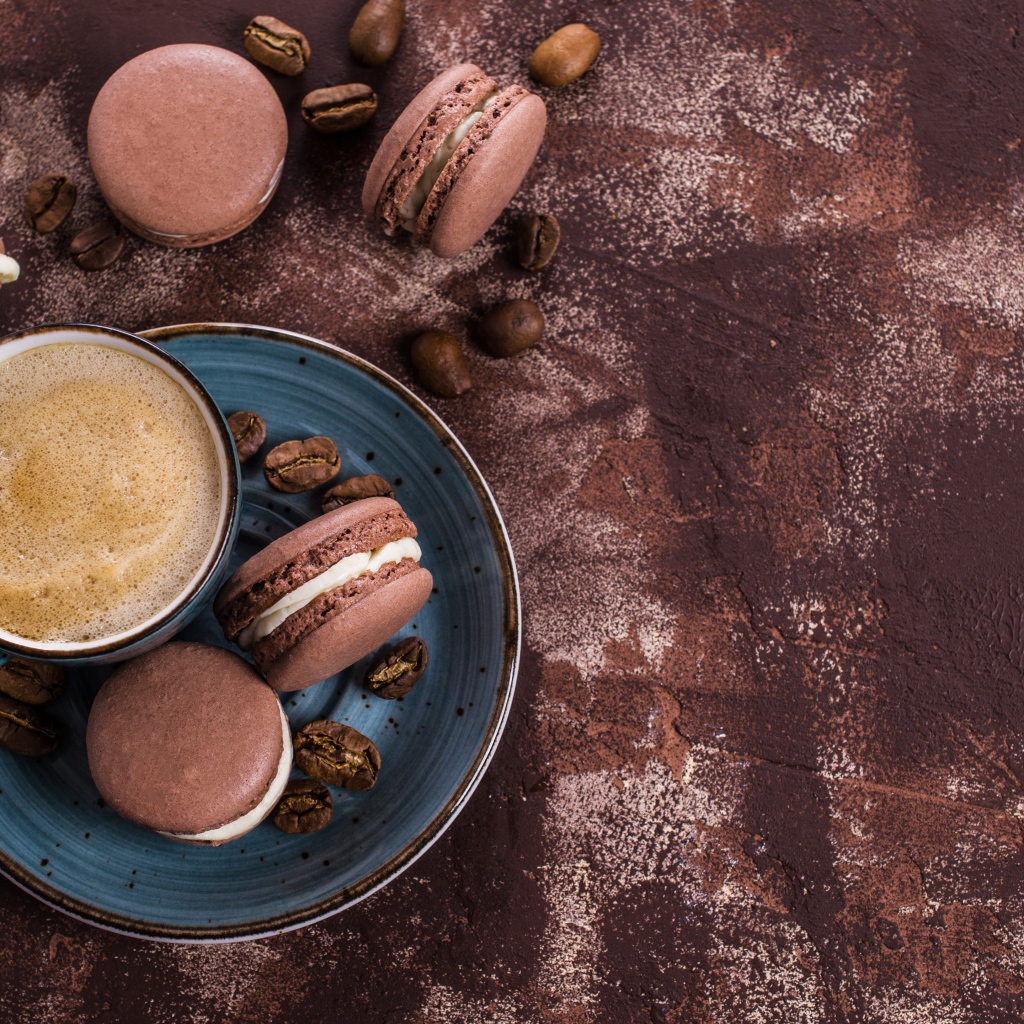 Чашка кофе с шоколадными макарунами на столе