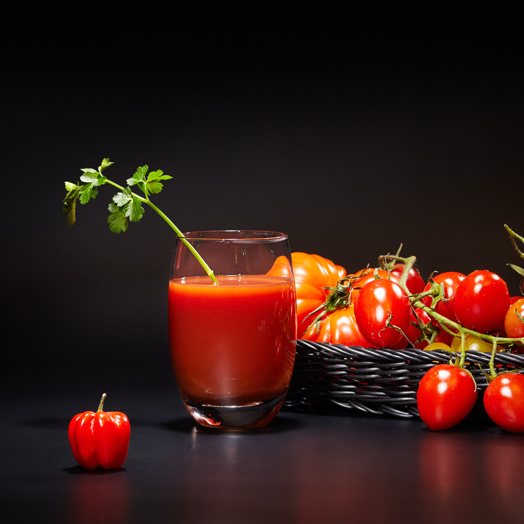 Стакан томатного сока на столе с помидорами