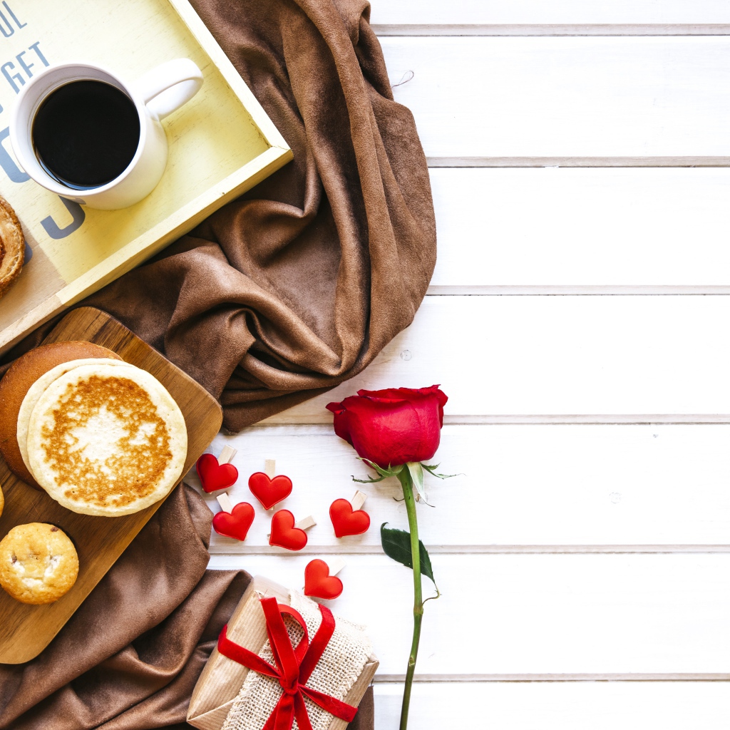 Выпечка на столе с кофе, подарком и красной розой