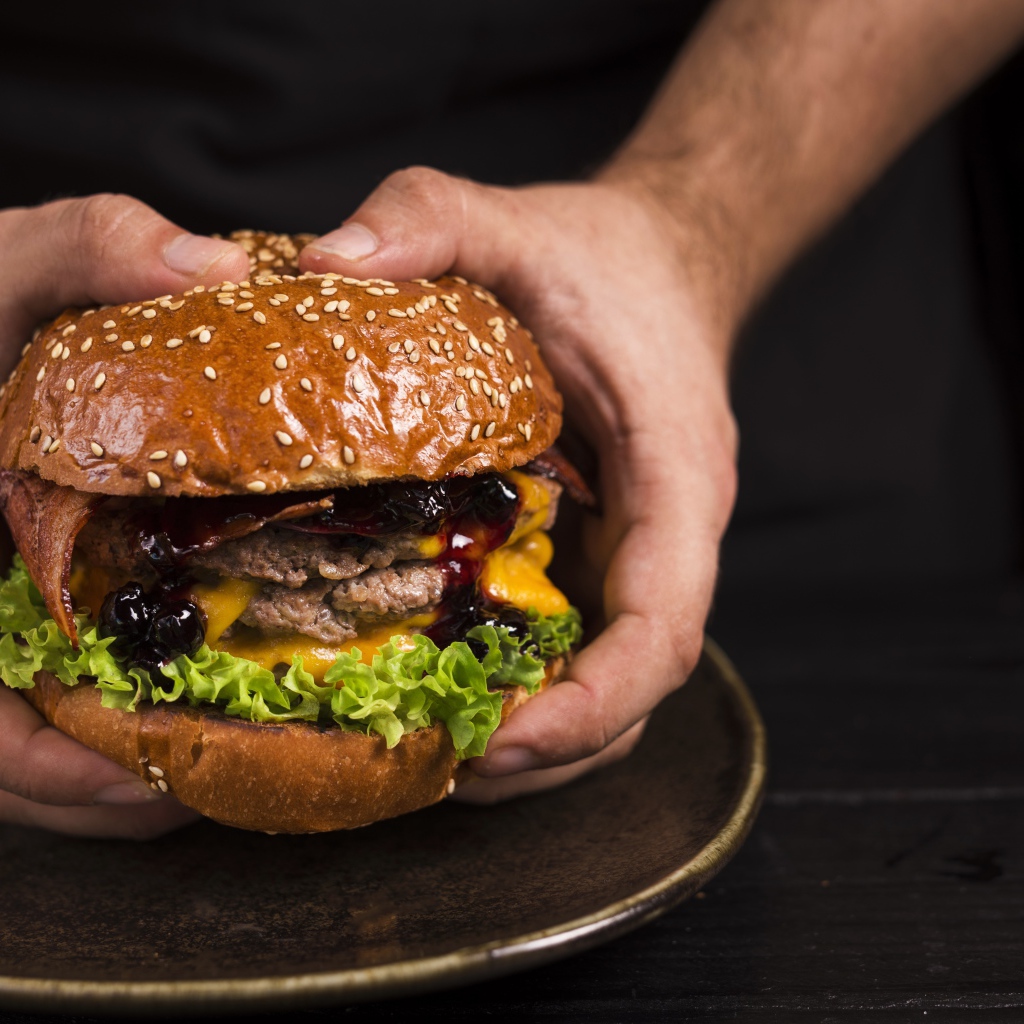 Большой сочный гамбургер в руках
