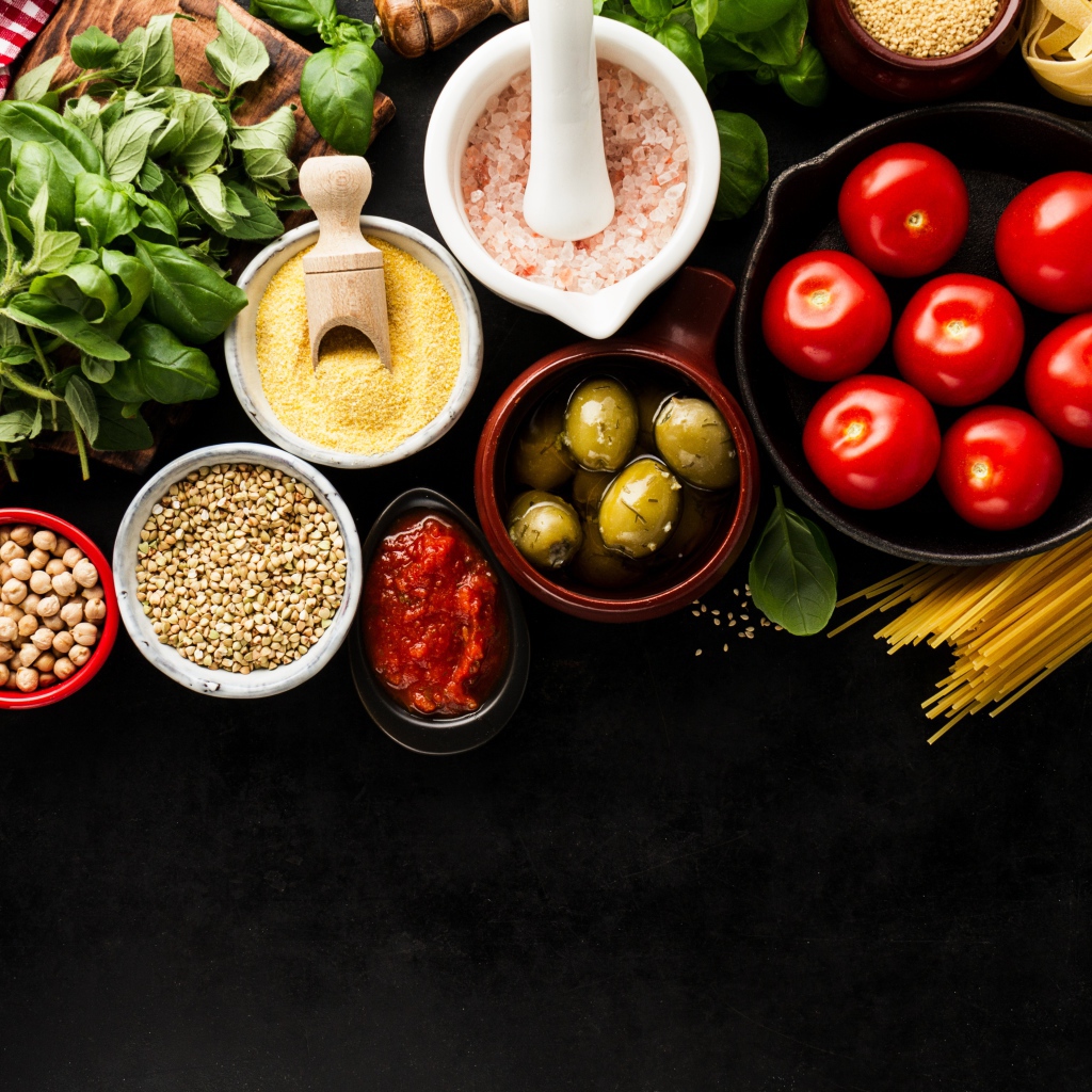 Крупы на столе с зеленью, помидорами, оливками и спагетти