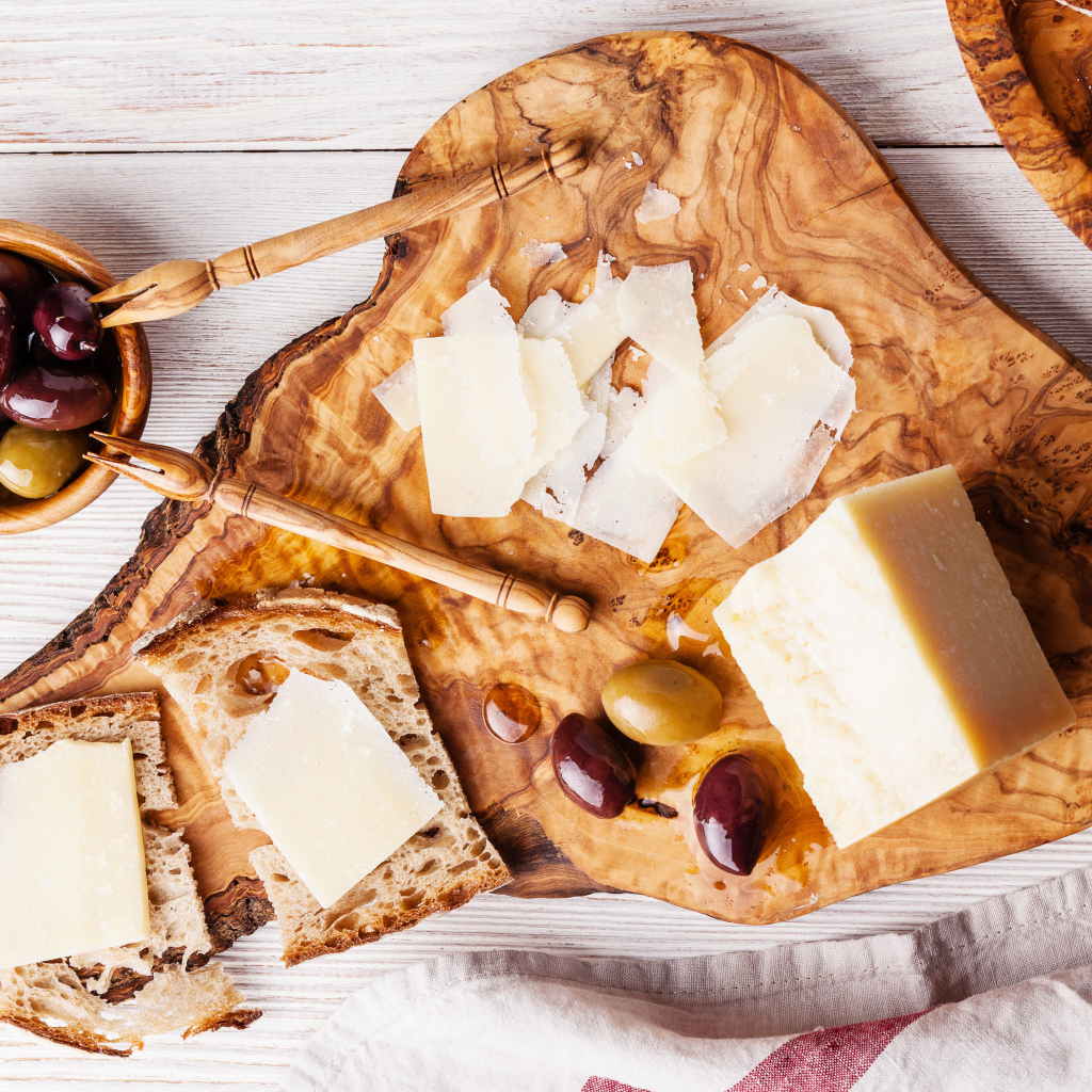 Сыр на доске с хлебом и и оливками