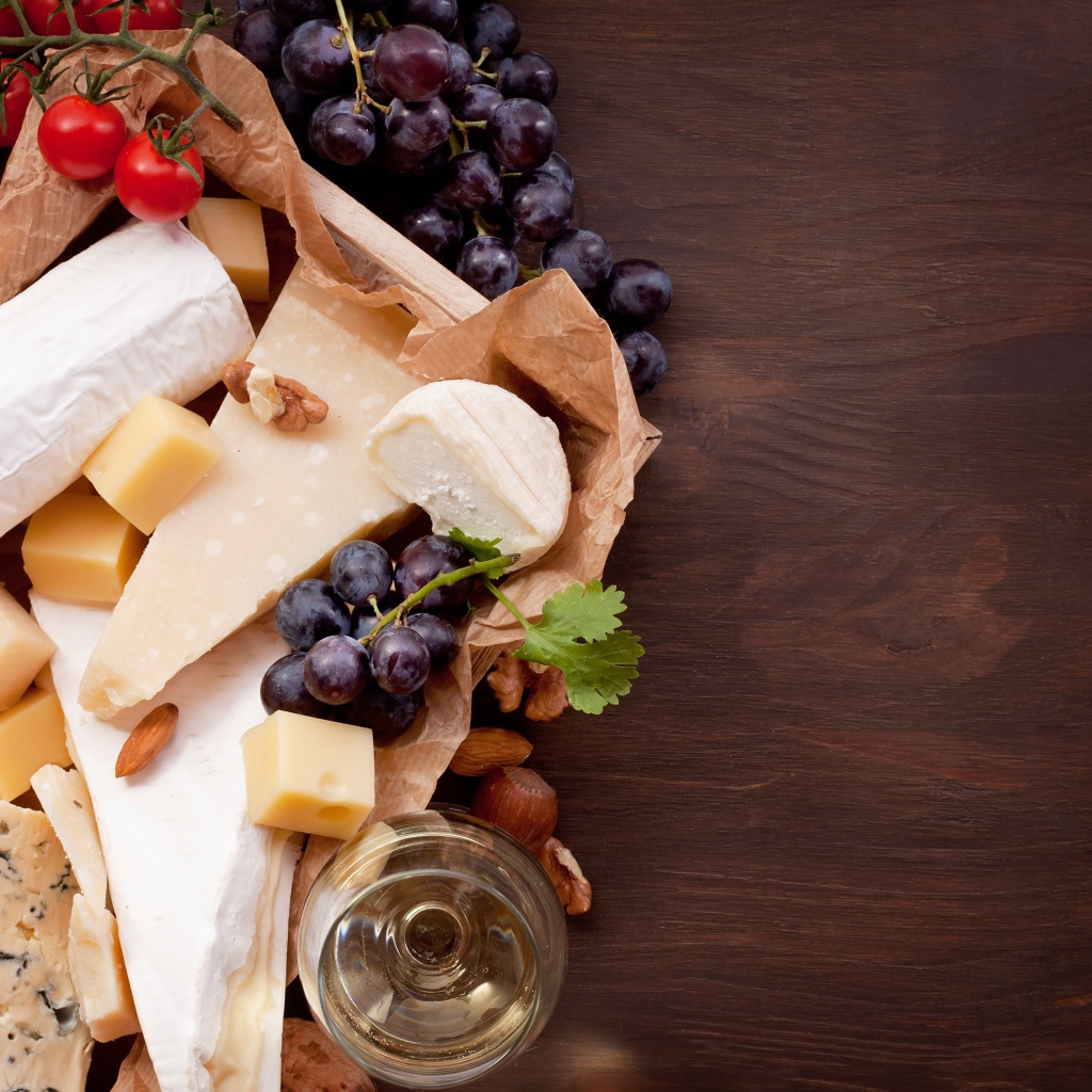 Сыр на столе с виноградом, инжиром и помидорами