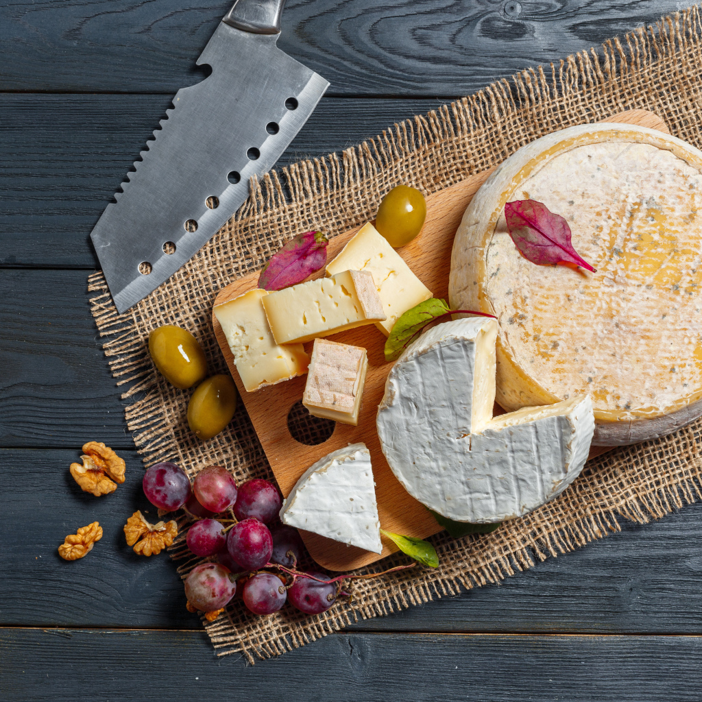 Сыр с плесенью на столе с орехами и виноградом 