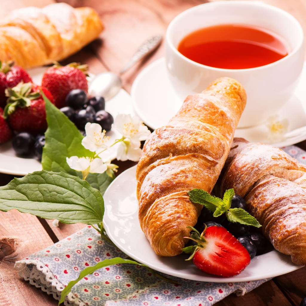 Круассаны на столе с ягодами и чашкой чая