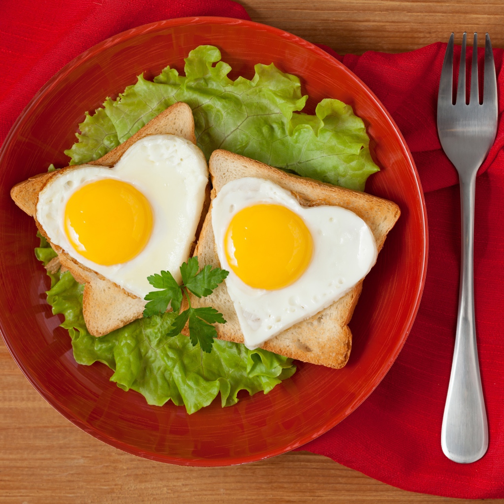 Гренки с яичницей на тарелке с листьями салата 