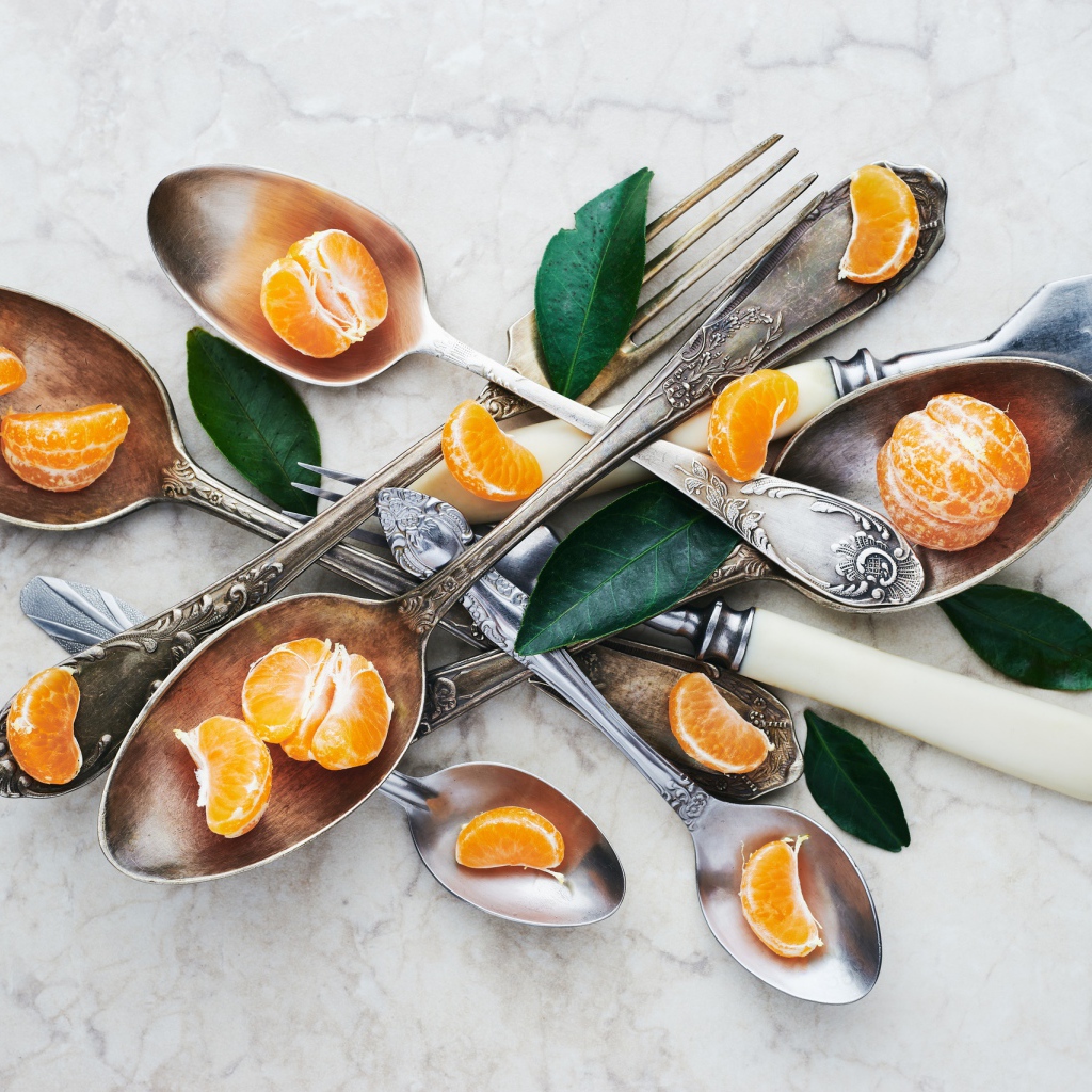 Столовые приборы на столе с дольками мандарина