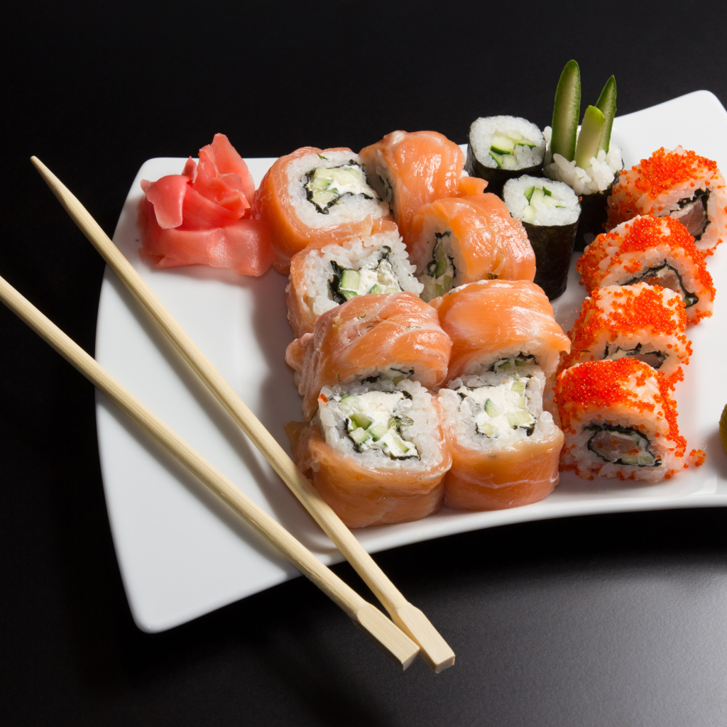 Вкусные японские суши на белой тарелке с палочками