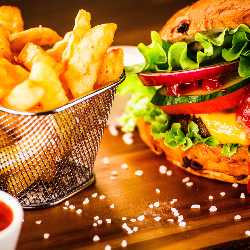 Аппетитный сочный гамбургер на доске с картошкой фри и соусом